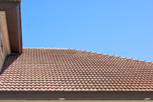 Peak of a clay tile roof with half round shingles against a blue sky in southern florida