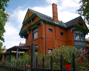 Large historic multi story brick home with hedges in City Park Denver.
